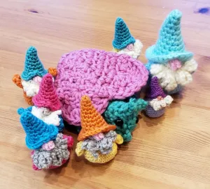 Crocheted toys, different sizes of gnomes surrounding a large Luvbug.